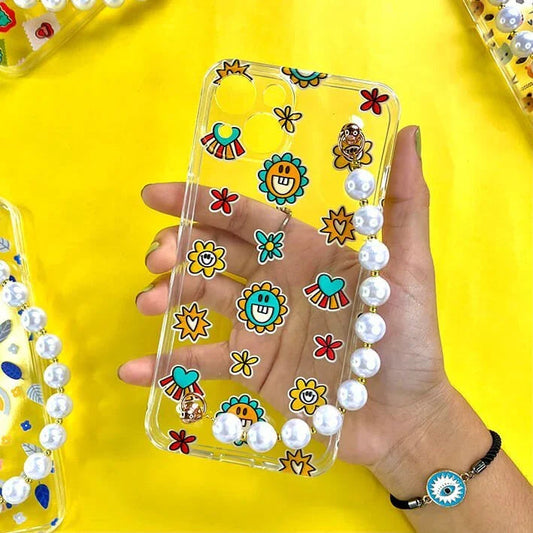 Clear phone case with colorful smiley flowers, hearts, and pearl chain on yellow background.
