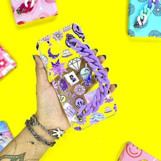 Hand holding a cute phone case with purple chain and cartoon charms on yellow background