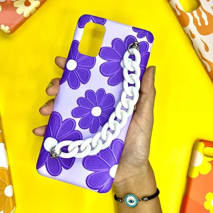 Purple floral phone case with white chain grip, held in hand, against yellow background