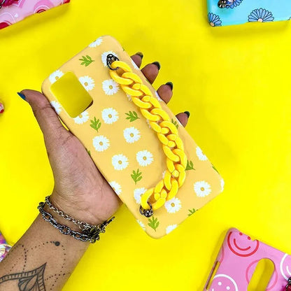Yellow daisy floral phone case with yellow chain handle, held by hand on yellow background