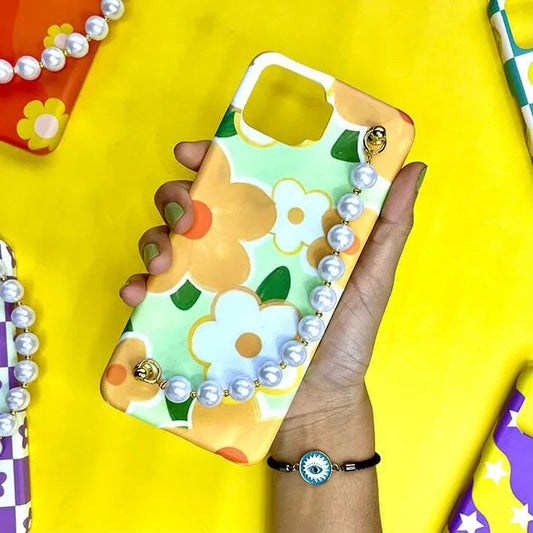Floral phone case with pearl chain charm held in hand on yellow background