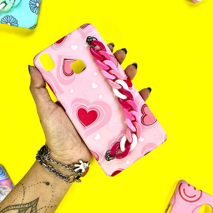 Pink phone case with heart pattern and pink chain charm, held against yellow background